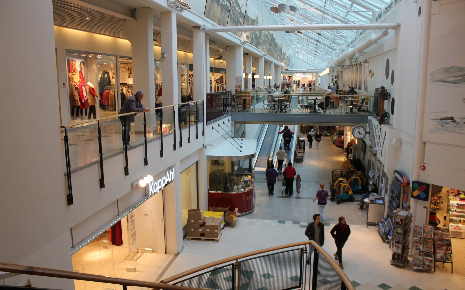 Interior of a shopping mall with modern retail storefronts and lighting
